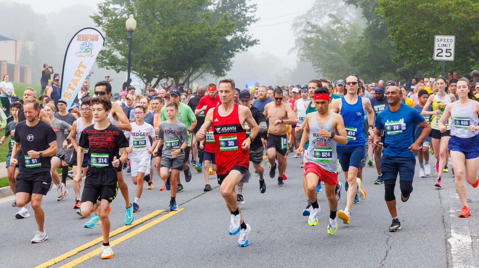 A group of runners running a race on a foggy day.