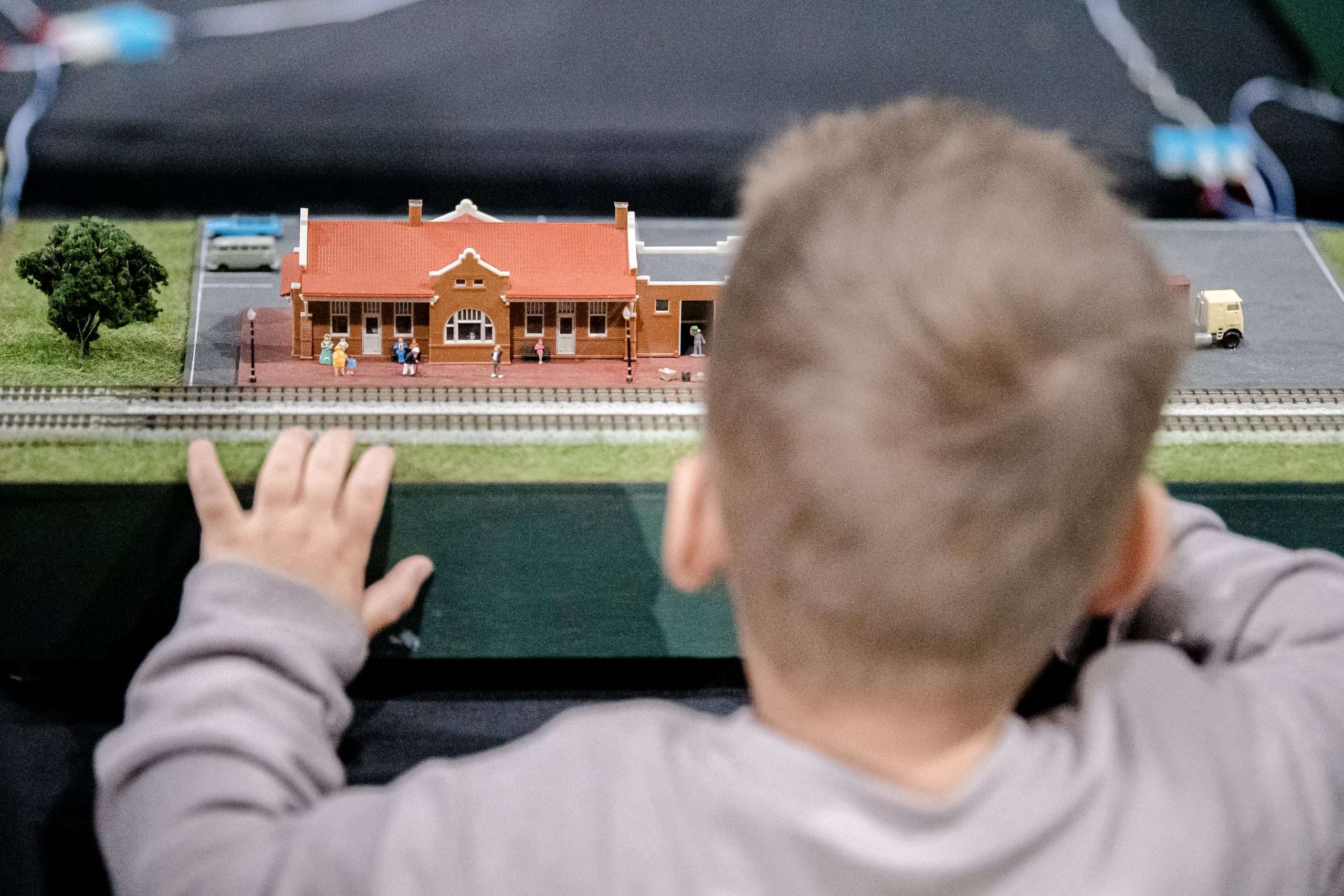Little boy standing in front of a model train and playing with it!