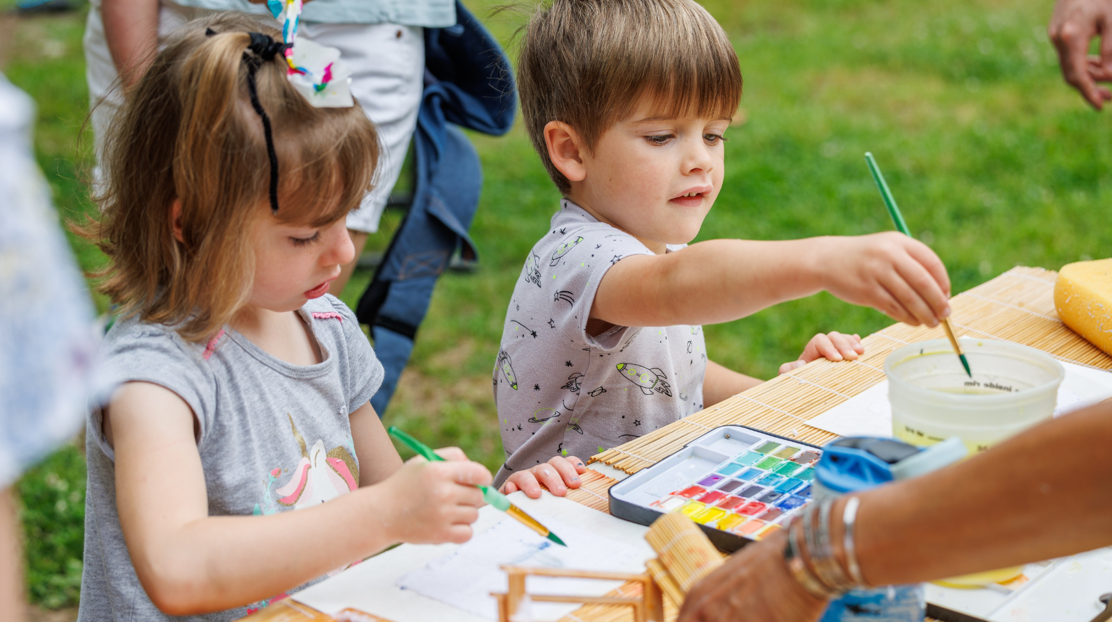 Children creating art with paint at a table in the garden, part of the kids' art program at Smith-Gilbert Gardens.