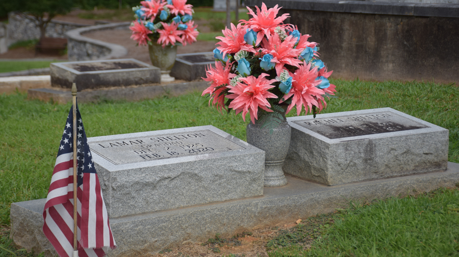 A grave adorned with a vase of colorful flowers and a small American flag, symbolizing remembrance and honor.