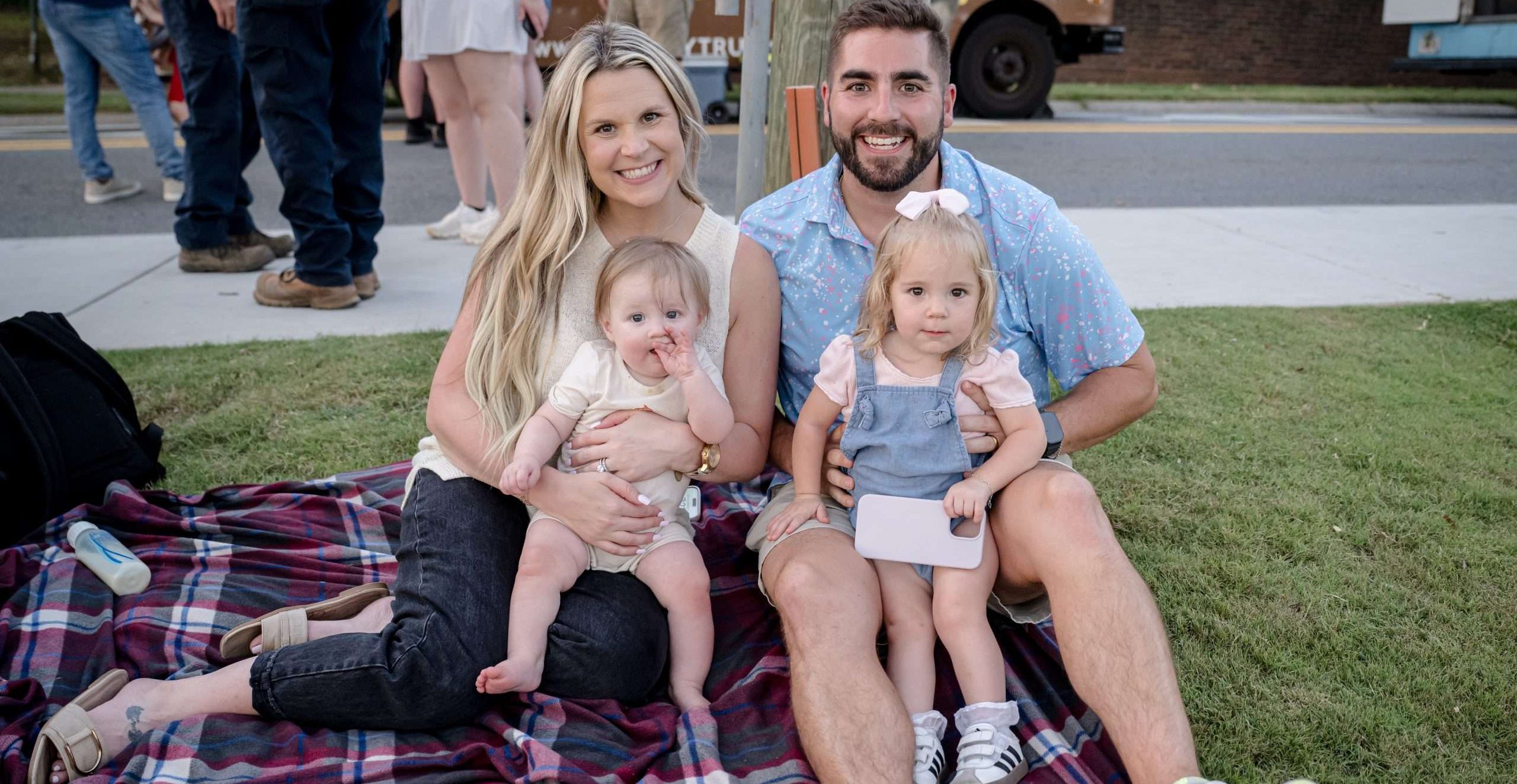 a couple holding their two kids in a park.