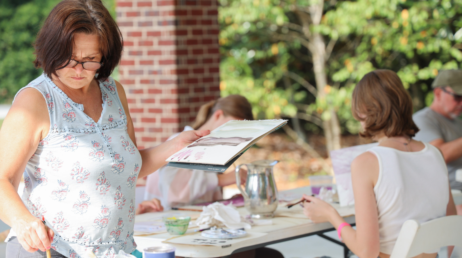 A women painting in front of class outdoors