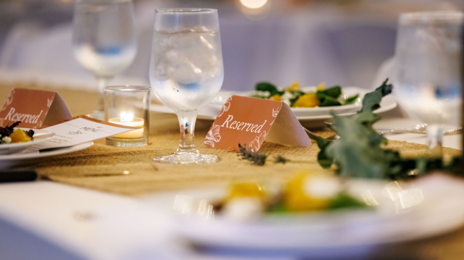 A dining table set with white plates and place settings, ready for guests at the Harvest Gathering in Smith-Gilbert Gardens.
