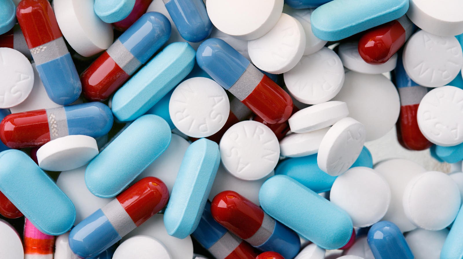 A mixed pile of blue, red, and white pills and capsules, featuring different shapes and sizes.